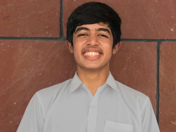 Mwanapwani Said, in uniform, smiling at the camera. She is sitting at a table with a notebook and laptop.